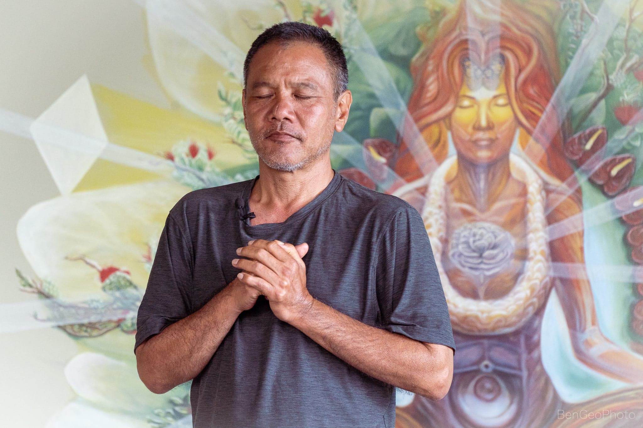 Kane standing in lush agroforest holding fresh Noni fruit